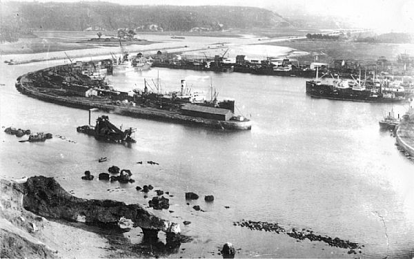 Panoramic view of the San Juan de Nieva dock with the rocks that make entry into the port difficult, where a dredger can be seen working on the navigation canal. This dock was modernised upon the increase in coal traffic at the end of the 19th century